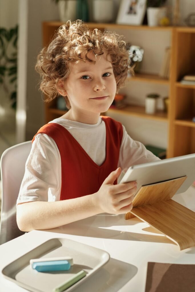 pexels photo 4145075 4145075 Curly-haired girl using tablet for online learning at home, sitting at desk.
